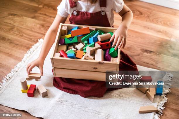 little girl cleaning up the toy box at home. - children playing with toys stockfoto's en -beelden