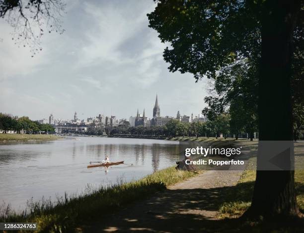 View from the banks of the Yarra River of the skyline of the City of Melbourne in Victoria State, Australia in October 1948. The tall spire of St...