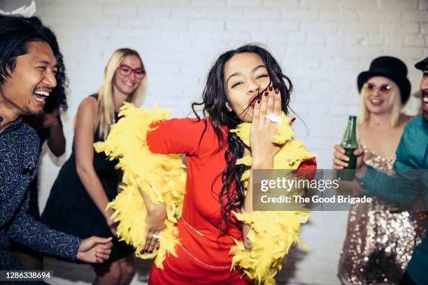 happy woman blowing kiss while dancing with friends at party - feather boa stock pictures, royalty-free photos & images