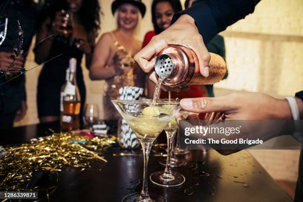 close-up of hands pouring drink in martini glass at party - bartender bildbanksfoton och bilder