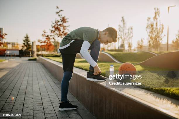 junge binden schnürsenkel vor der praxis - basketball shoe stock-fotos und bilder