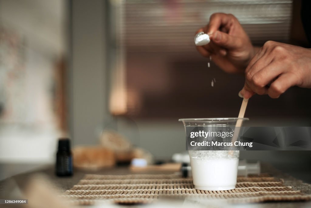 Asiática china hembra vertiendo bicarbonato de sodio a una taza de agua