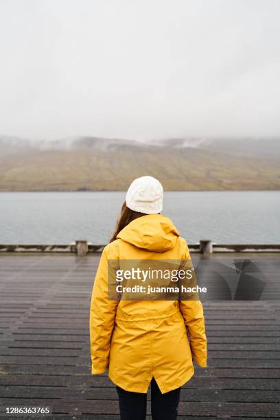 traveling woman in raincoat on pier - passenger train stockfoto's en -beelden