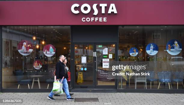 People walk past a Costa Coffee store on November 18, 2020 in Crewe, Cheshire. The United Kingdom will continue to impose lockdown measures until...