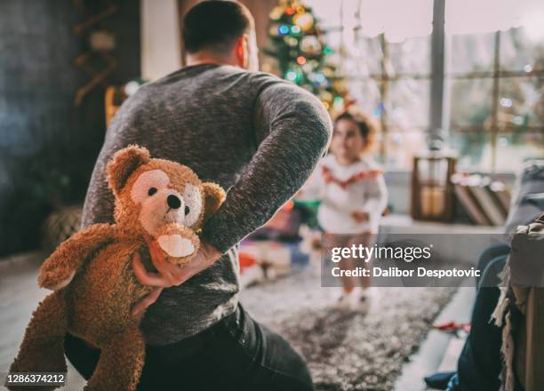 dad holds a teddy bear behind his back. - hands behind back stock photos et images de collection