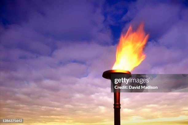 flaming torch at sunset - international multi sport event stock pictures, royalty-free photos & images