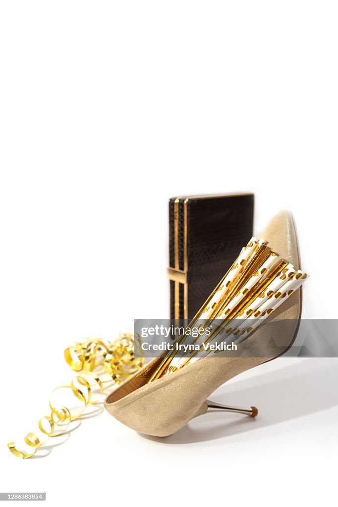 Gold high heel shoe filled with cocktail straws and Сhristmas decoration.