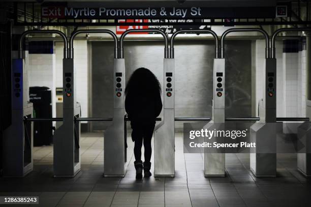 Woman exits a Brooklyn subway station on November 18, 2020 in New York City. In a bid to save save $1.2 billion, the Metropolitan Transportation...