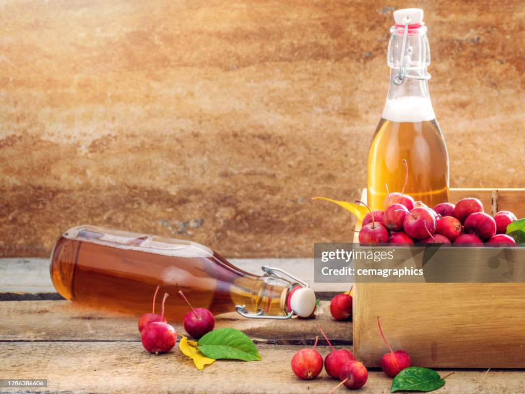 Apple Juice Vinegar with Miniature Japanese Apples on Wooden Board in Morning Time