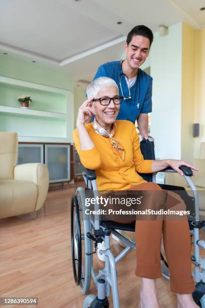 an older disabled woman is receiving a positive advice from a young doctor at home. - elderly receiving paperwork stock pictures, royalty-free photos & images