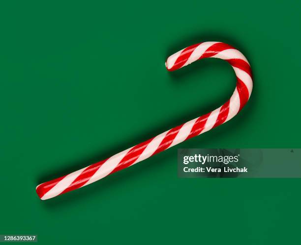 pattern of christmas candy canes on green background. the sticks run in all directions and out of the frame. - candy cane fotografías e imágenes de stock