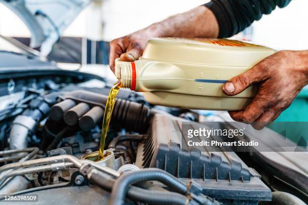車のエンジンに油を注ぐ。車へのオイル交換中に注がれた新鮮なモーターオイル - 潤滑油 ストックフォトと画像