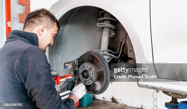 car mechanic hands replace brakes in garage - replacement stock pictures, royalty-free photos & images