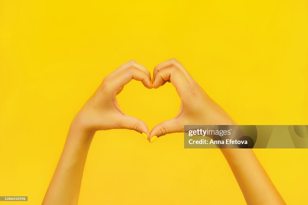 Woman showing heart sign with fingers. Trending bright background of the year. Charity concept.