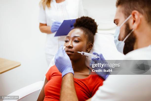 beautiful young woman receiving filler injection in lips - lip injections stock pictures, royalty-free photos & images