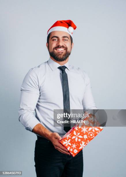 happy male professional holding christmas present - santa hat stock pictures, royalty-free photos & images