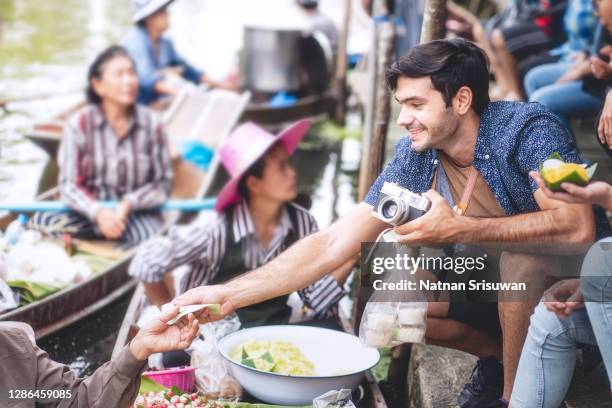 foreigner buying thai desserts from sailor who making food on a boat. - country market stockfoto's en -beelden