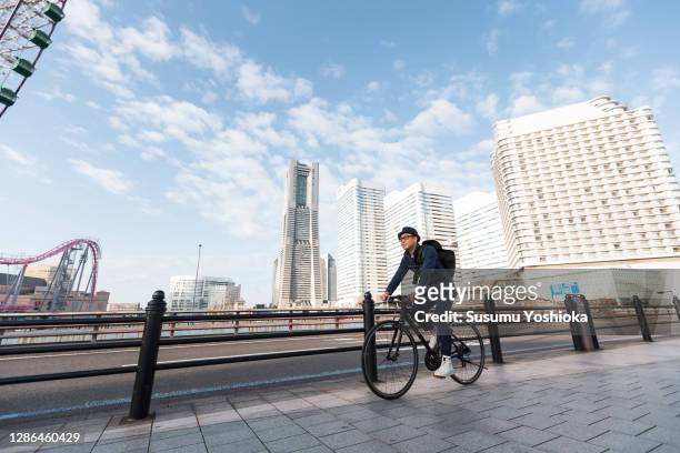 a man rides a bicycle to work in the town of bayside in the morning - commuter cyclist stock pictures, royalty-free photos & images