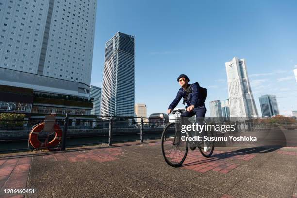 a man rides a bicycle to work in the town of bayside in the morning - stadtbezirk naka yokohama stock-fotos und bilder