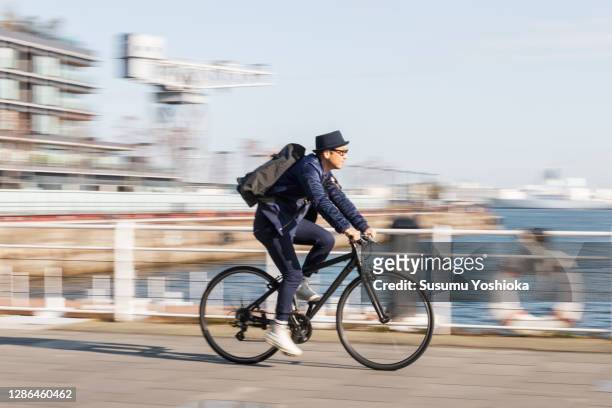 a man rides a bicycle to work in the town of bayside in the morning - ciclismo fotografías e imágenes de stock