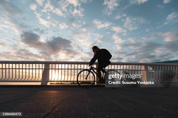 a man rides a bicycle to work in the town of bayside in the morning - men's cycling stock pictures, royalty-free photos & images