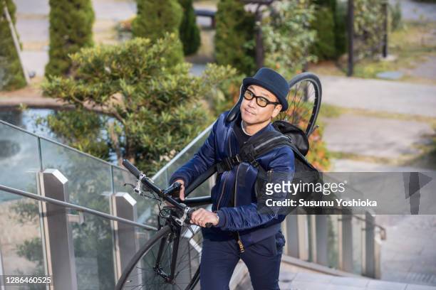 a man rides a bicycle to work in the town of bayside in the morning - 階段　のぼる ストックフォトと画像
