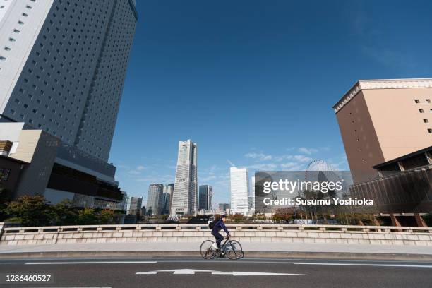 a man rides a bicycle to work in the town of bayside in the morning - minato mirai imagens e fotografias de stock