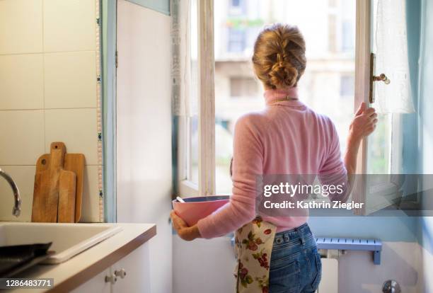 woman opening kitchen window, holding a bowl - female neckline stock pictures, royalty-free photos & images