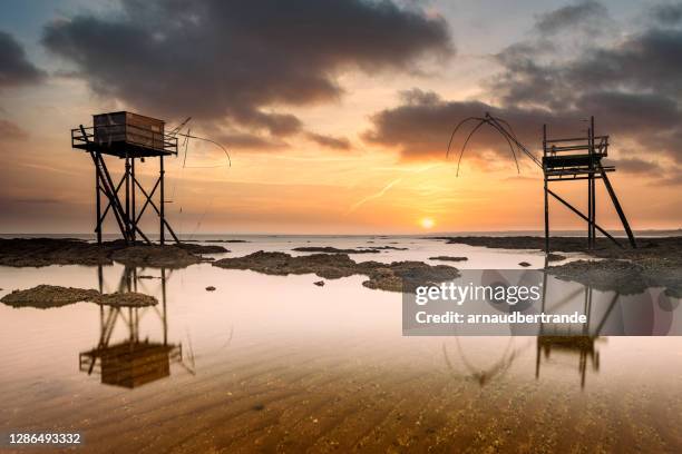 fishing huts on beach at low tide at sunset, saint-michel-chef-chef, loire-atlantique, france - loire atlantique stock pictures, royalty-free photos & images