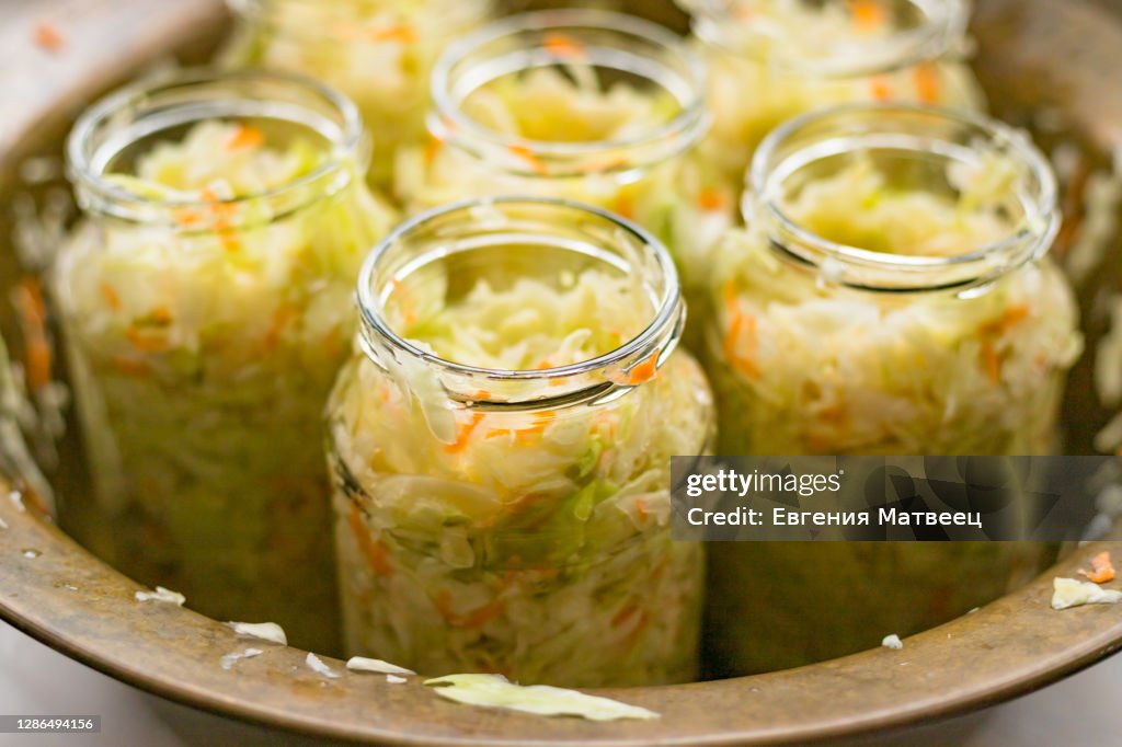 Sauerkraut fermentation in copper bowl, glass pot. Cut white cabbage fermented by lactic acid bacteria