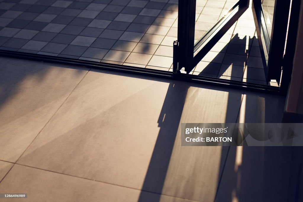 Sun-lit doorway showing abstract shadows on floor tiles