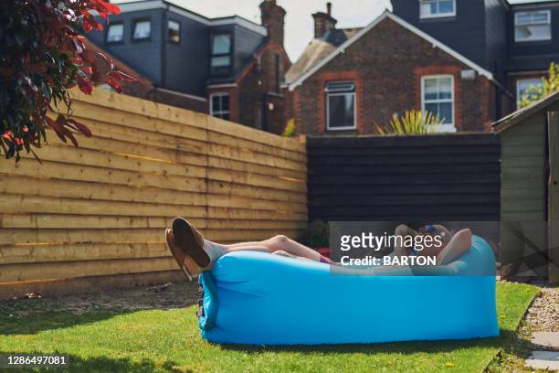 man relaxes on inflatable lounger in garden at home - cloture maison photos et images de collection