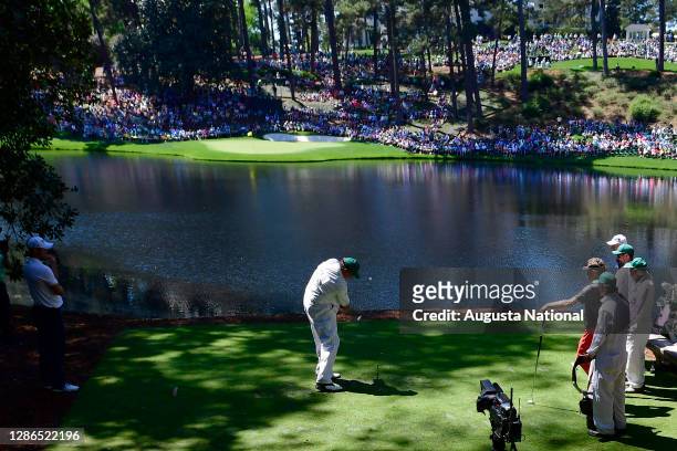 The caddie for Masters champion Larry Mize hits from the No. 9 tee box during the Par 3 Contest for the Masters at Augusta National Golf Club,...
