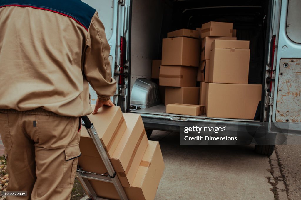 Zusteller verpackt Kartons in Lieferwagen