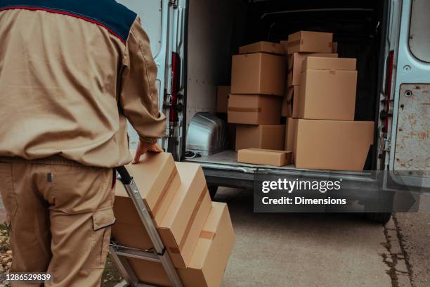 delivery man packing cardboard boxes in van - entregador imagens e fotografias de stock