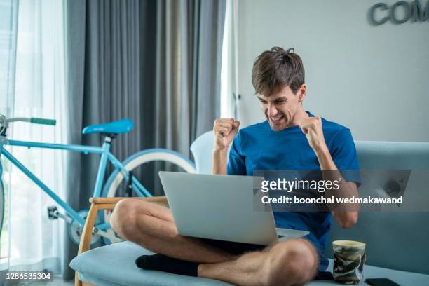 excited millennial man in glasses sit at table in kitchen feel euphoric win online lottery on laptop, overjoyed young male in spectacles look at computer screen triumph get good news on email - auction stock pictures, royalty-free photos & images