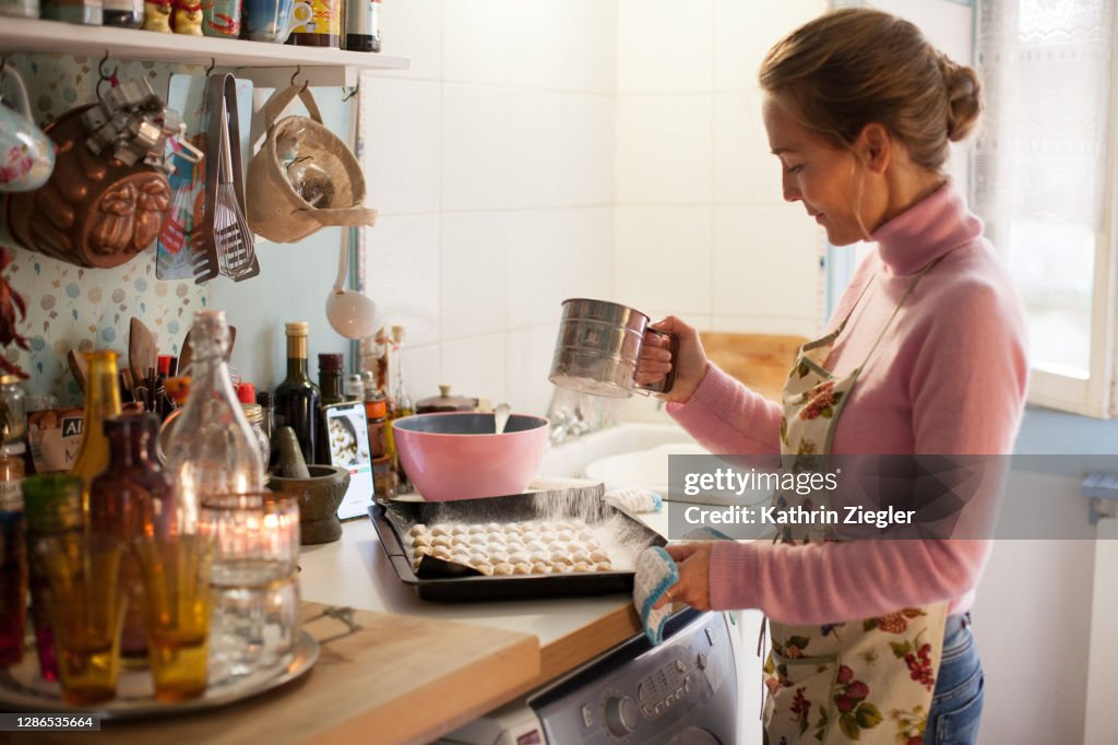 Woman sprinkling powdered sugar on freshly baked Christmas cookies