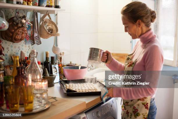 woman sprinkling powdered sugar on freshly baked  christmas cookies - woman baking stock pictures, royalty-free photos & images