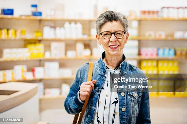 portrait of mature woman smiling in local pharmacy - prescription glasses stock pictures, royalty-free photos & images