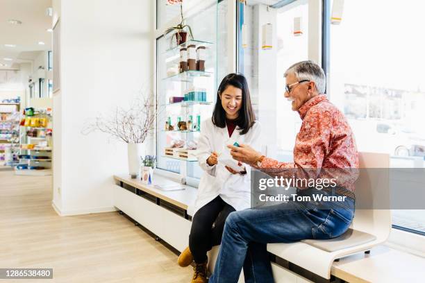 pharmacist discussing medication with senior gentleman - pharmacy stock-fotos und bilder