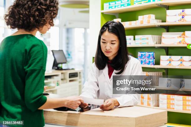 chemist discussing prescription with customer - pharmacy stock-fotos und bilder