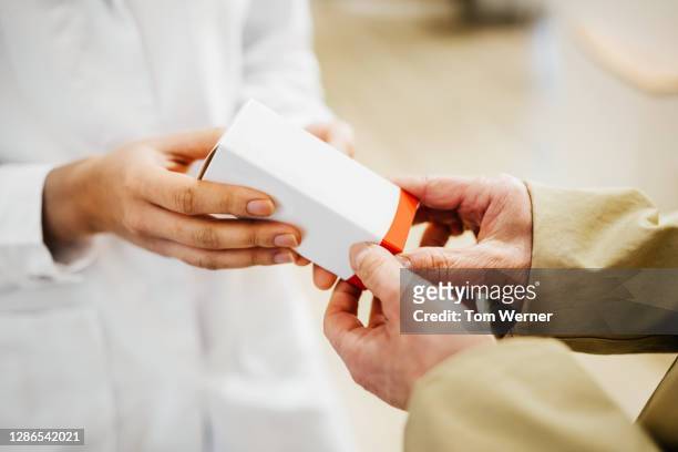 pharmacist giving medication to customer - box hand stock-fotos und bilder