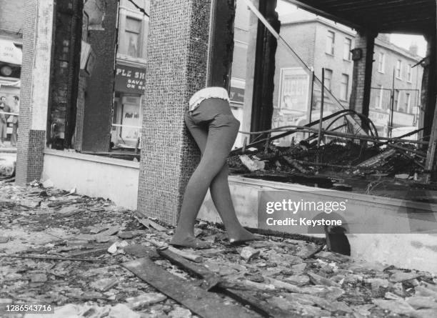 The lower half of a mannequin stands among the debris of a destroyed shop after a night of violence during rioting in Brixton, London, England, 13th...