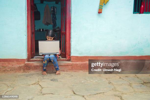 indisch dorpsmeisje dat laptopcomputersysteem zittingen bij huisgang werkt - indian school kids stockfoto's en -beelden