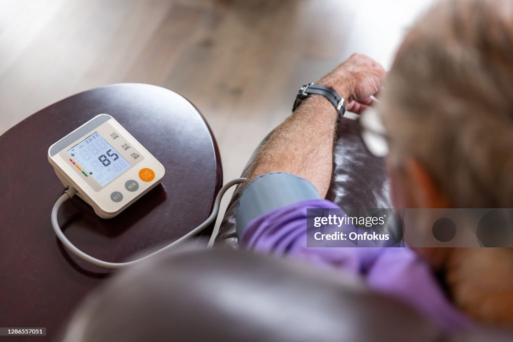 Senior Man checking blood pressure on Auto blood pressure Machine at home