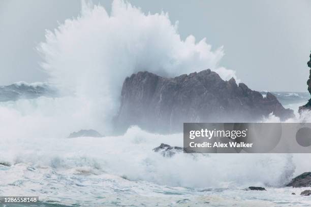 large waves breaking over rocks - waves crashing on rocks stock pictures, royalty-free photos & images