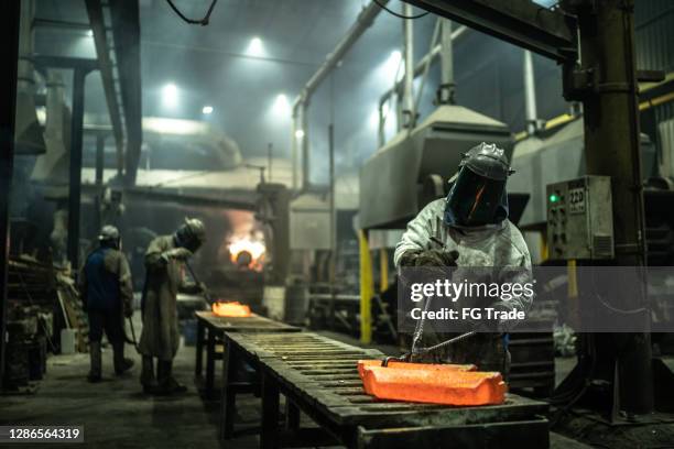metal industry work - removing hot iron using tweezers - foundry worker stock pictures, royalty-free photos & images
