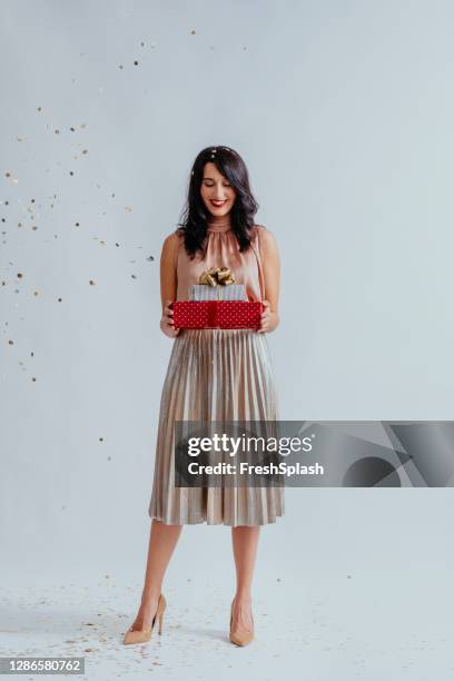 verticale de studio d’une belle jeune femme aux cheveux noirs retenant une pile de cadeaux d’anniversaire - cadeau danniversaire photos et images de collection