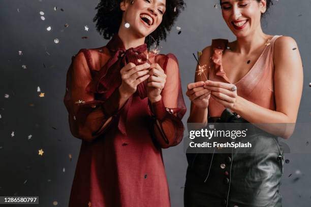 happy couple vieren kerstmis samen door holding ontstoken sterretjes onder een douche van confetti - christmas party dress stockfoto's en -beelden