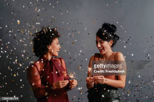 happy couple vieren kerstmis samen door holding ontstoken sterretjes onder een douche van confetti - couple celebrating stockfoto's en -beelden